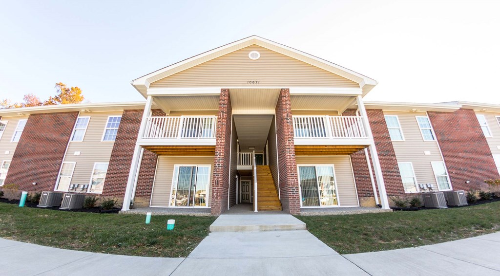 the front exterior of a brick building with stairs and a sidewalk